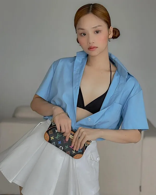 Ảnh sexy miu lê có một người phụ nữ mặc áo sơ mi màu xanh và váy trắng cầm ví