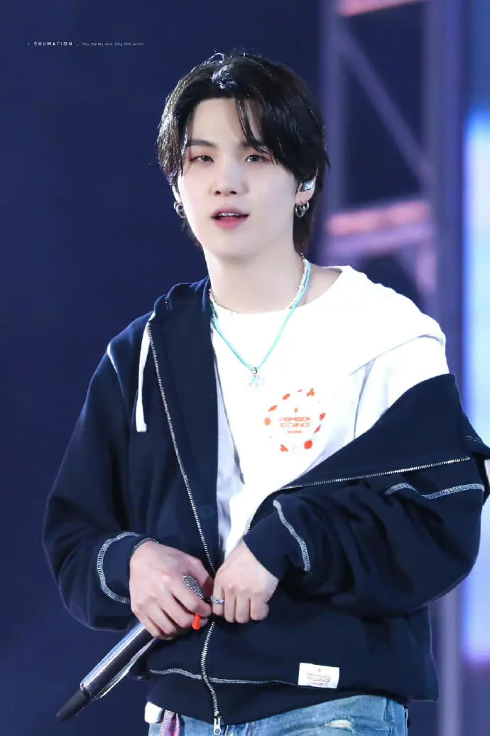 Ảnh suga bts có một người đàn ông đang cầm micro trong tay