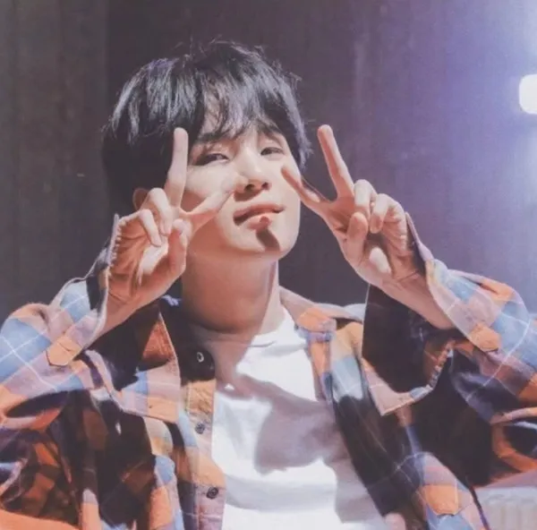 Ảnh suga bts có một chàng trai trẻ làm dấu hiệu hòa bình với đôi tay của mình