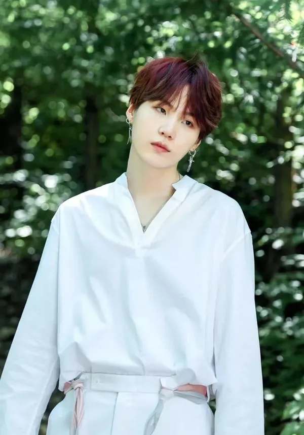 Ảnh suga bts có một người đàn ông đang đứng trước số cây