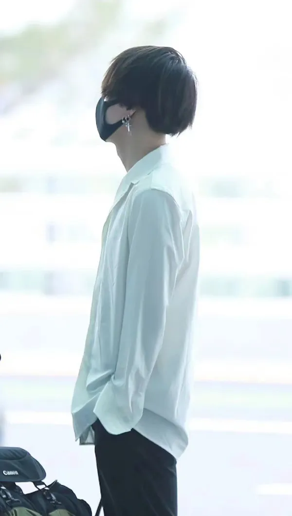 Ảnh suga bts có một người phụ nữ đang đứng cạnh túi hành lý
