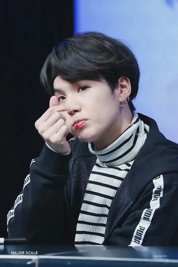 Ảnh suga ngầu cậu bé k-pop với mái tóc ngắn mặc áo len sọc đen và trắng ngồi bàn