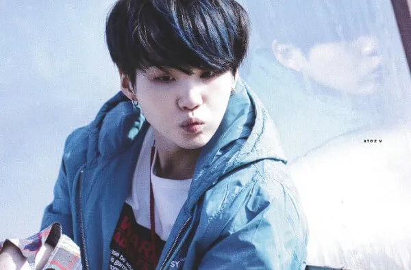 Ảnh suga bts có một chàng trai trẻ mặc áo khoác màu xanh cầm điện thoại di động
