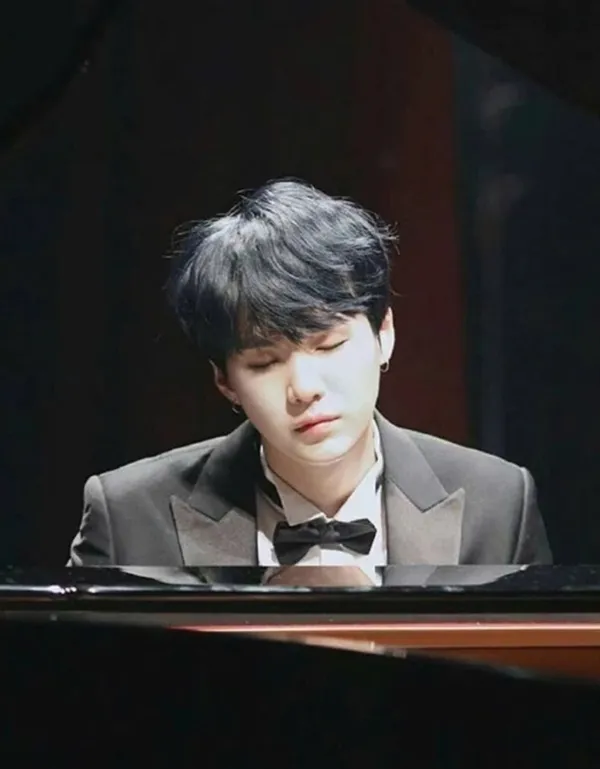 Ảnh suga ngầu có một chàng trai trẻ trong bộ tuxedo chơi đàn piano
