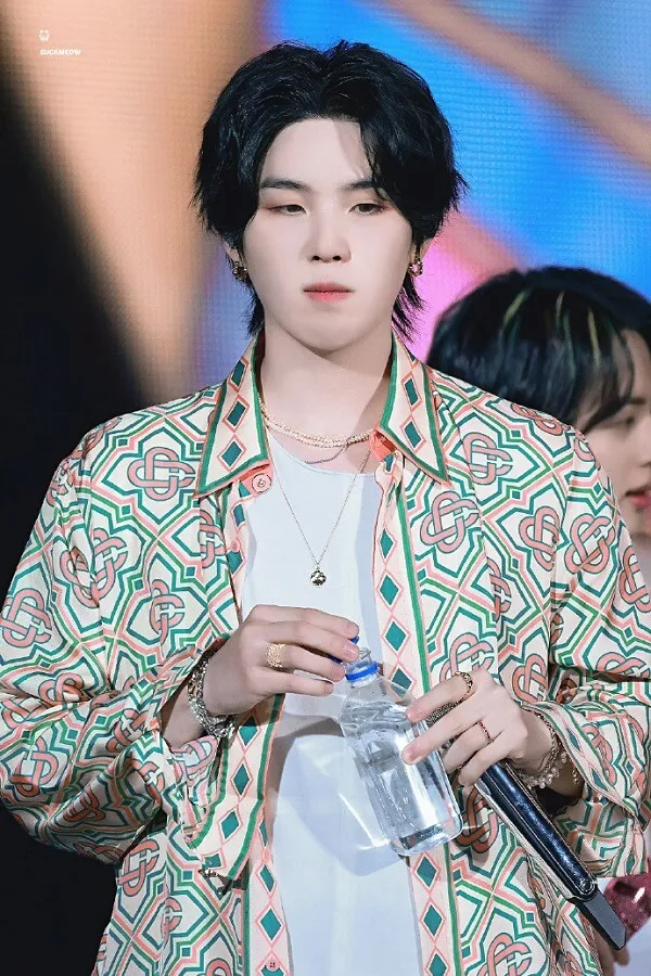 Ảnh suga bts có một người đàn ông đang đứng với micro trong tay