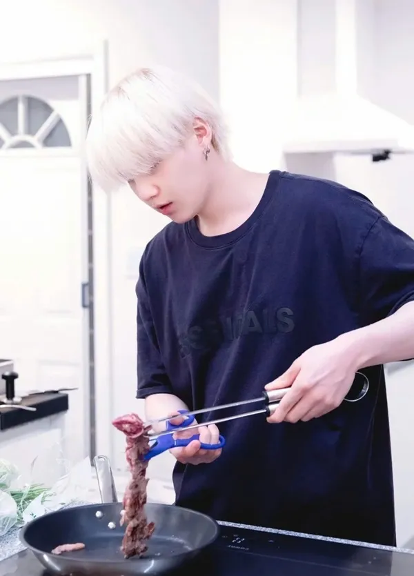 Ảnh suga mới nhất cậu bé tóc vàng trong nhà bếp chuẩn bị thức ăn với kẹp trên chảo rán