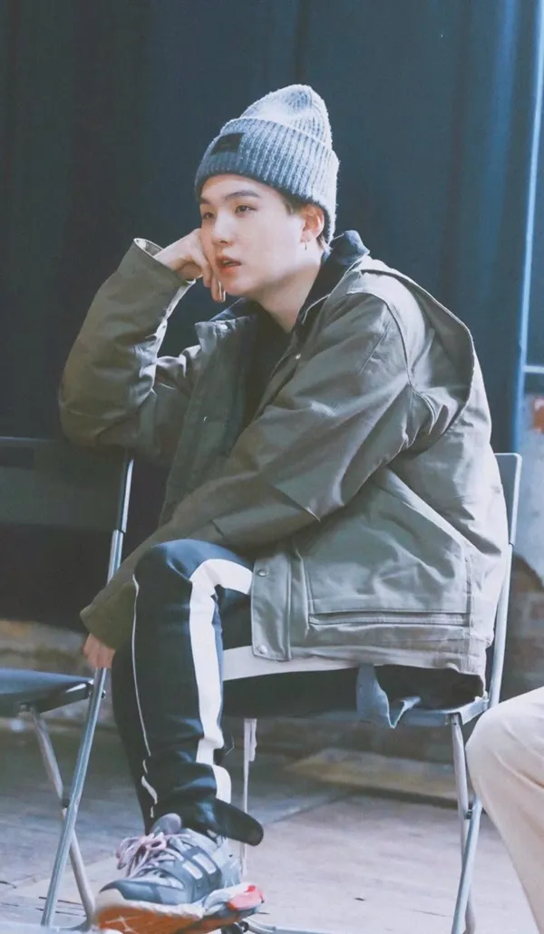 Ảnh suga mới nhất có một người đàn ông ngồi trên ghế nói chuyện điện thoại di động