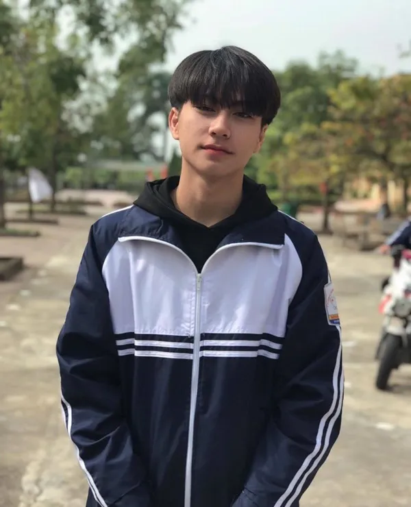 Ảnh trai đẹp học sinh có một chàng trẻ đang đứng trong bãi đậu xe với chiếc máy phía sau