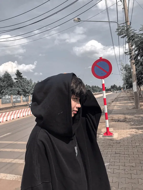 Ảnh trai đẹp lớp có một người đàn ông mặc áo hoodie màu đen đứng bên đường