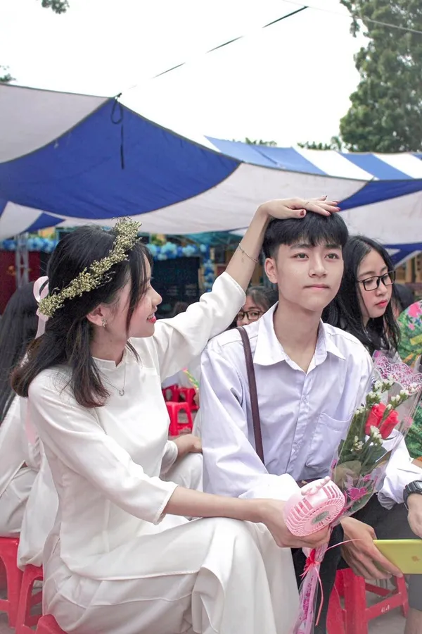 Ảnh trai đẹp học sinh che mặt có một người đàn ông và phụ nữ đang ngồi trên những chiếc ghế màu đỏ