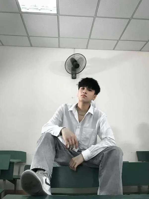 Ảnh trai đẹp lớp ai đó đang ngồi trên một chiếc ghế dài trong căn phòng với những màu xanh lá cây và người hâm mộ