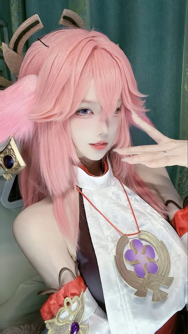 Ảnh yae miko cosplay có một người phụ nữ mái tóc màu hồng mặc trang phục và cầm thanh kiếm