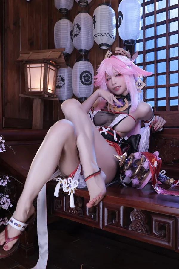 Ảnh yae miko cute có một người phụ nữ đang ngồi trên chiếc ghế dài với mái tóc màu hồng