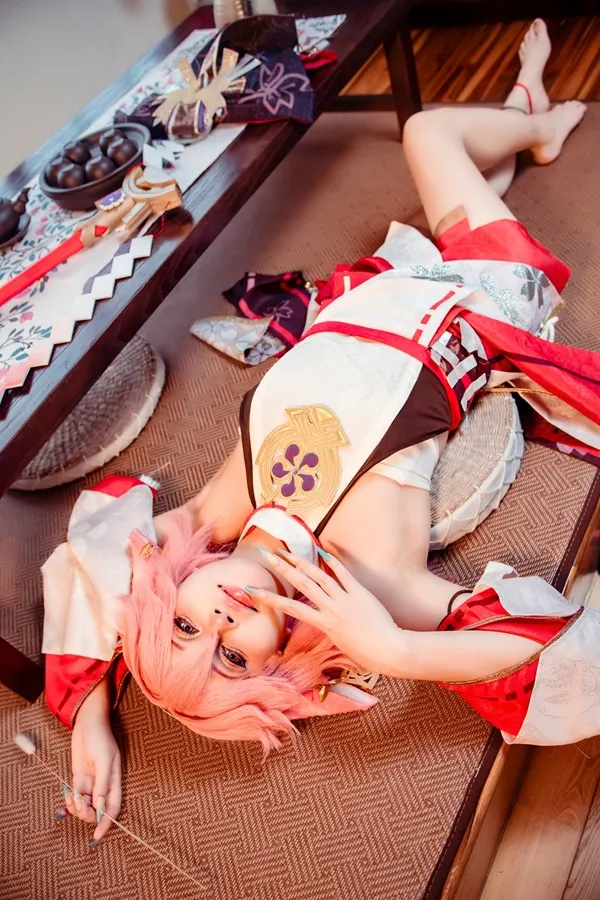 Ảnh yae miko cosplay có một người phụ nữ đang nằm trên sàn nhà với mái tóc màu hồng