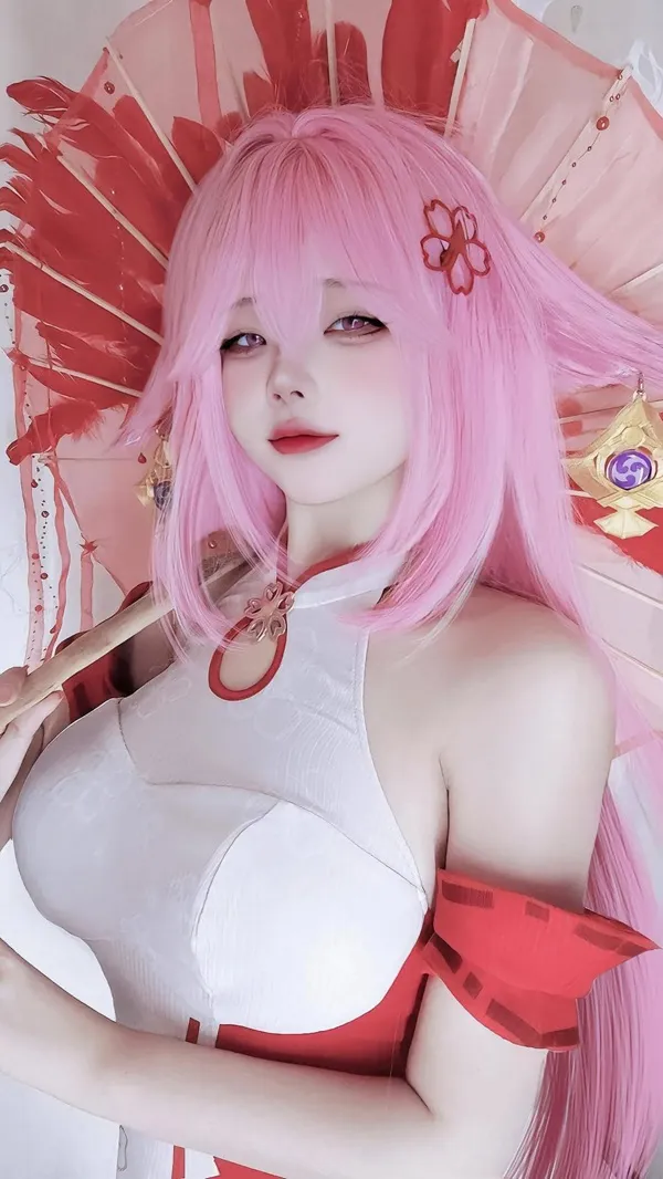 Ảnh yae miko cosplay có một người phụ nữ mái tóc màu hồng cầm chiếc