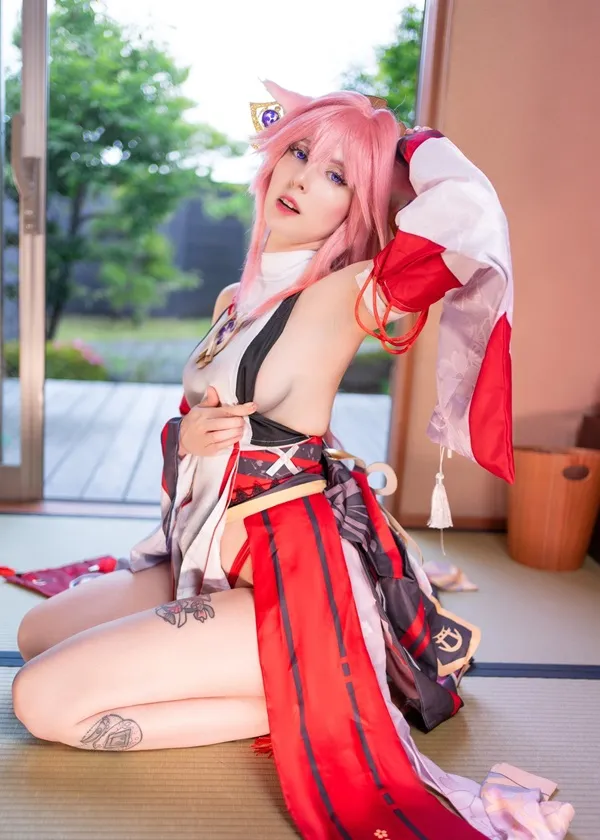 Ảnh yae miko cosplay người phụ nữ khỏa thân với mái tóc màu hồng ngồi trên sàn trước cửa sổ