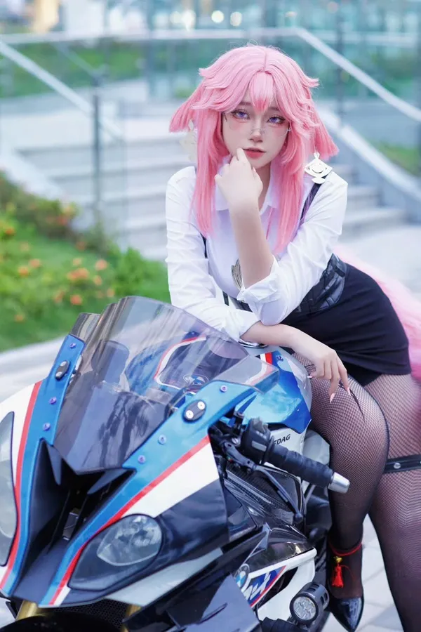 Ảnh yae miko cosplay người phụ nữ tóc hồng ngồi trên xe máy tạo dáng cho một bức tranh