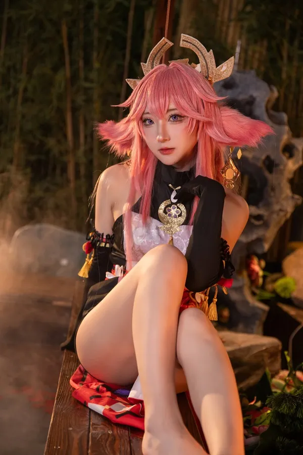 Ảnh yae miko cute có một người phụ nữ đang ngồi trên chiếc ghế dài với mái tóc màu hồng