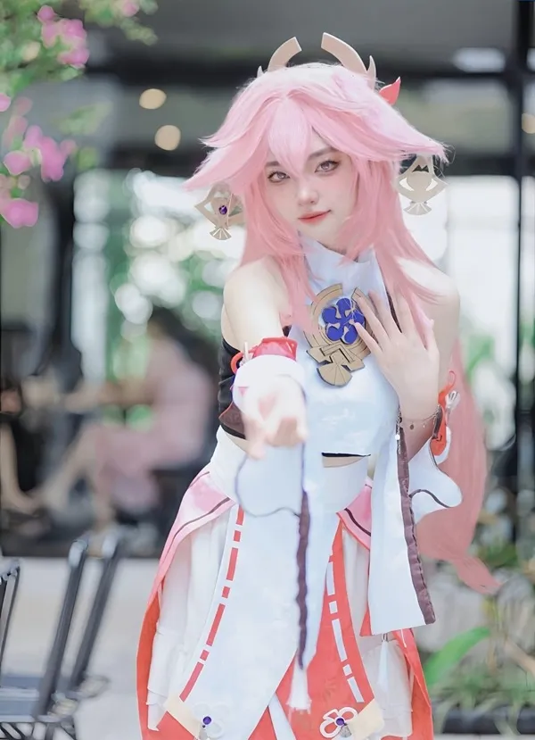 Ảnh yae miko cute có một người phụ nữ mái tóc màu hồng mặc trang phục và cầm cốc