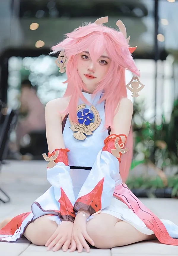 Ảnh yae miko cute có một người phụ nữ mái tóc màu hồng ngồi trên mặt đất