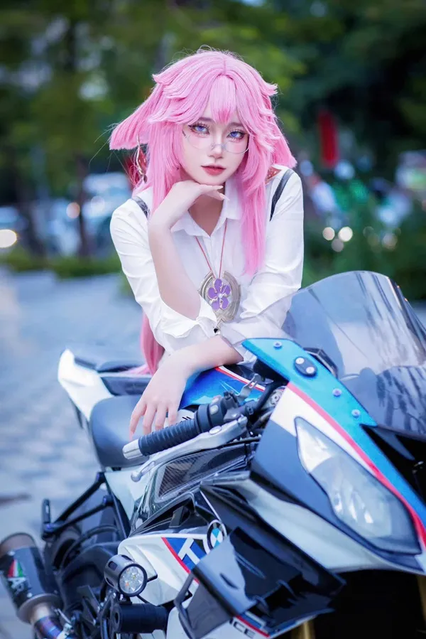 Ảnh yae miko cute có một người phụ nữ mái tóc màu hồng ngồi trên xe máy
