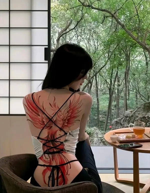 Có một người phụ nữ ngồi trên ghế với hình xăm lưng