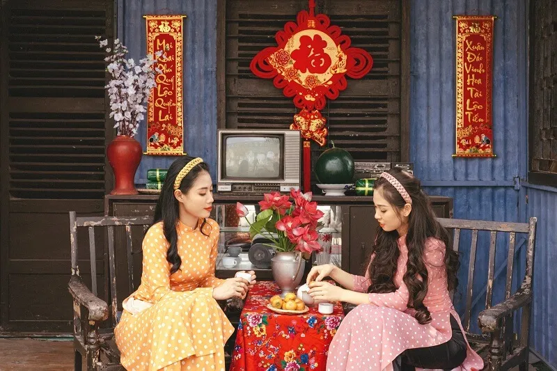 Chụp ảnh tết có hai người phụ nữ ngồi trên băng ghế nói chuyện với nhau