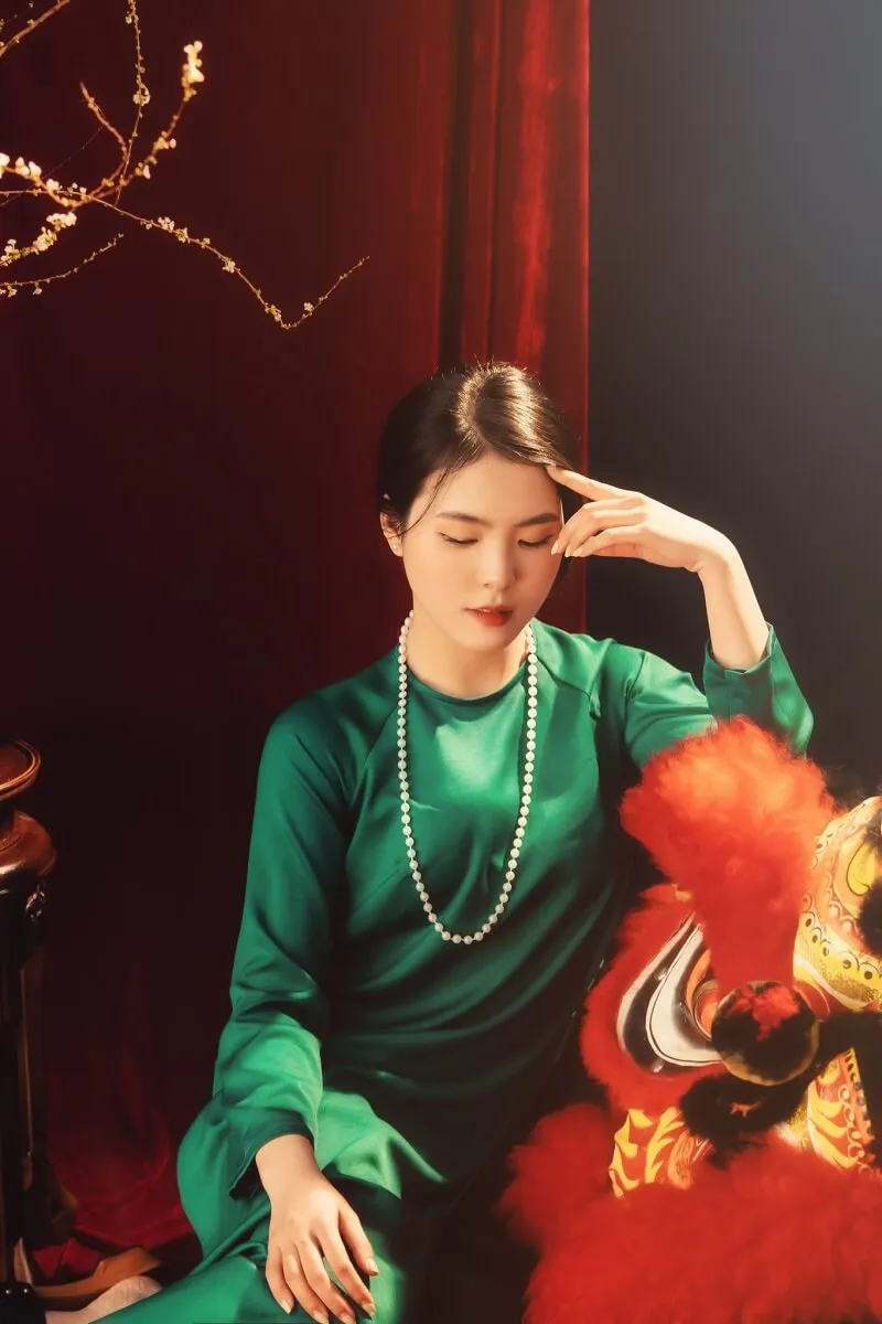 Chụp ảnh tết có một người phụ nữ mặc chiếc váy màu xanh lá cây ngồi cạnh con sư tử