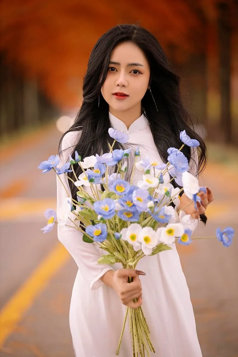 Chụp ảnh tết có một người phụ nữ mặc chiếc váy trắng cầm bó hoa