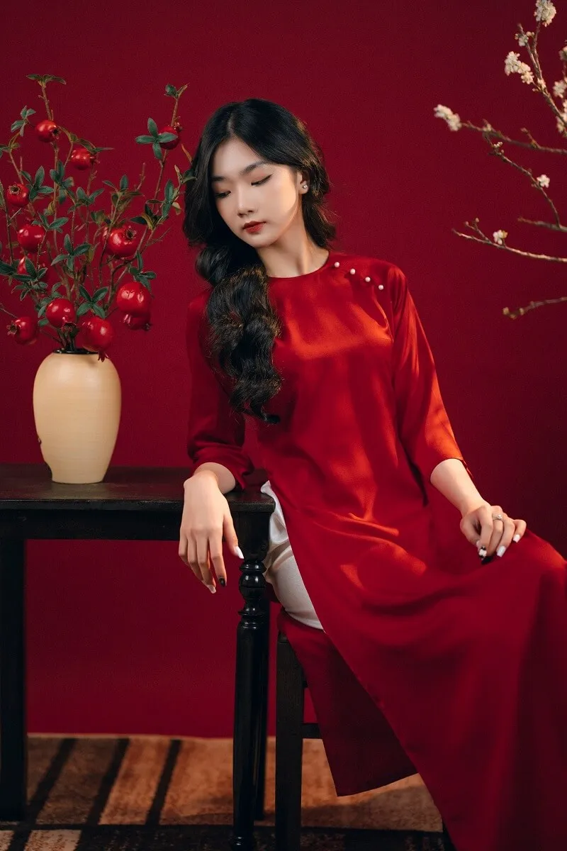 Dáng chụp ảnh tết có một người phụ nữ ngồi trên bàn với chiếc bình hoa