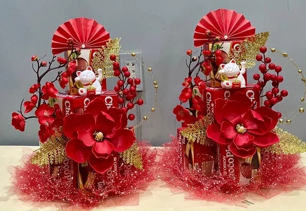 Có hai bình hoa màu đỏ và đồ trang trí trên đó