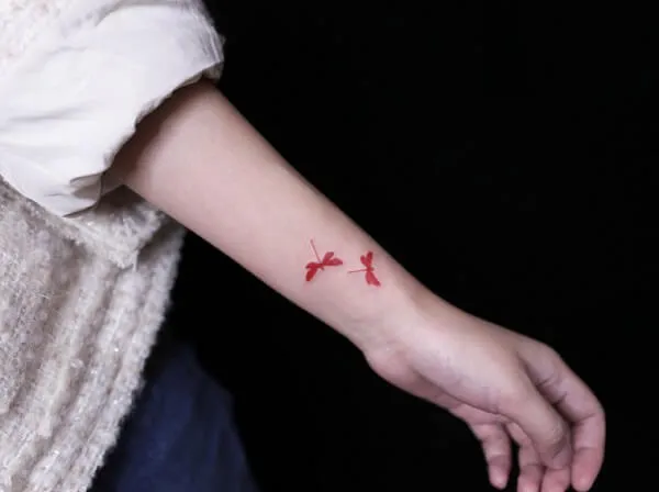 Có một cánh tay của người phụ nữ với hình xăm hai con chim trên đó