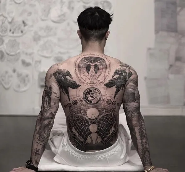 Có một người đàn ông ngồi trên sàn với hình xăm lưng