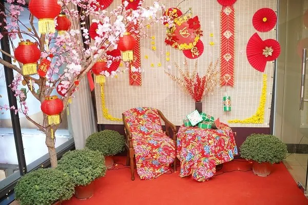 Có một thảm đỏ với hai chiếc ghế và cái cây phía trước nó