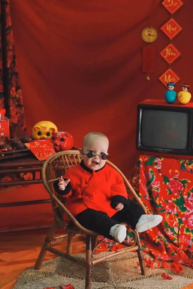 Concept chụp ảnh tết cho bé có một em đang ngồi trên ghế trước tv