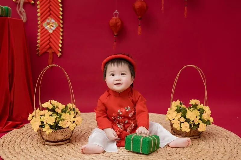 Concept chụp ảnh tết cho bé có một em đang ngồi trên sàn nhà với số hoa