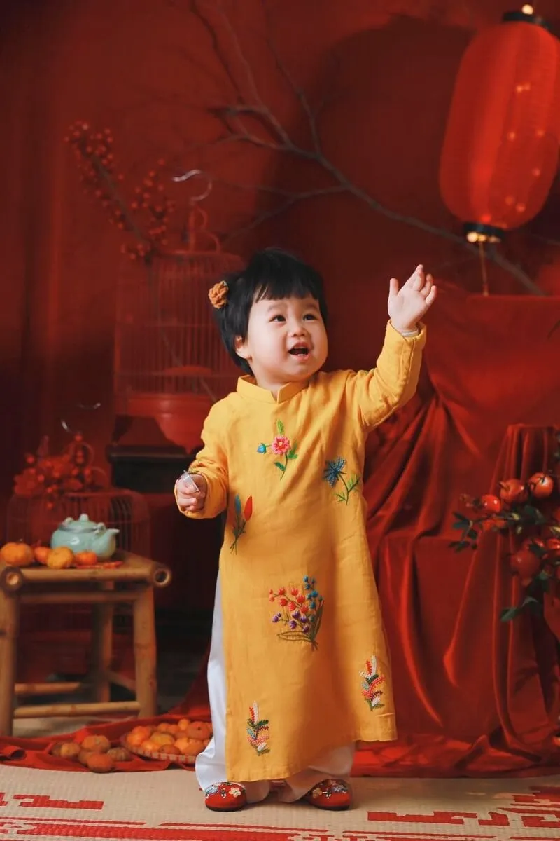 Concept chụp ảnh tết cho bé sơ sinh đây là hình của một cô mặc váy màu vàng