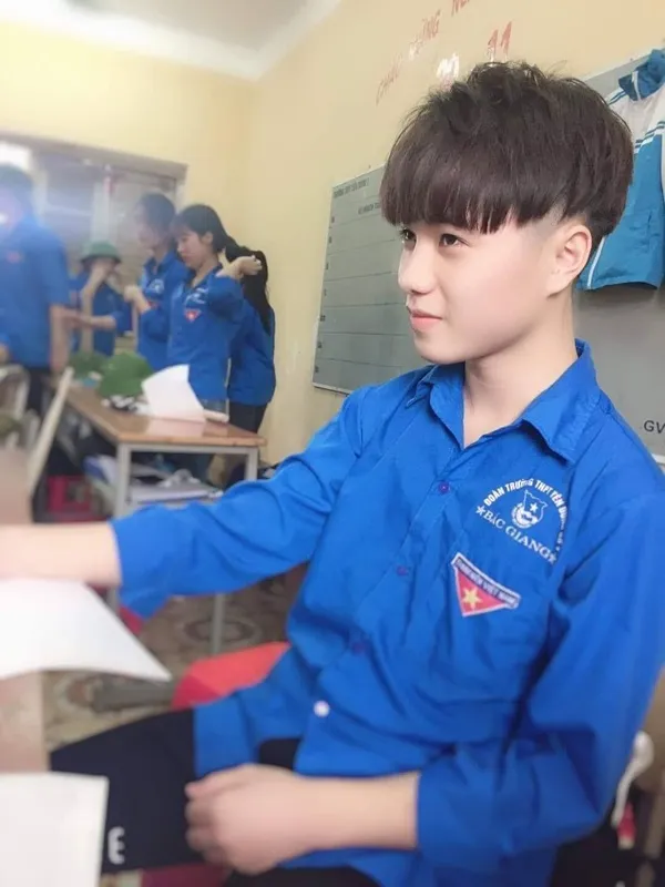 Ảnh trai đẹp đi học có một cậu bé mặc áo sơ mi màu xanh ngồi bàn làm việc