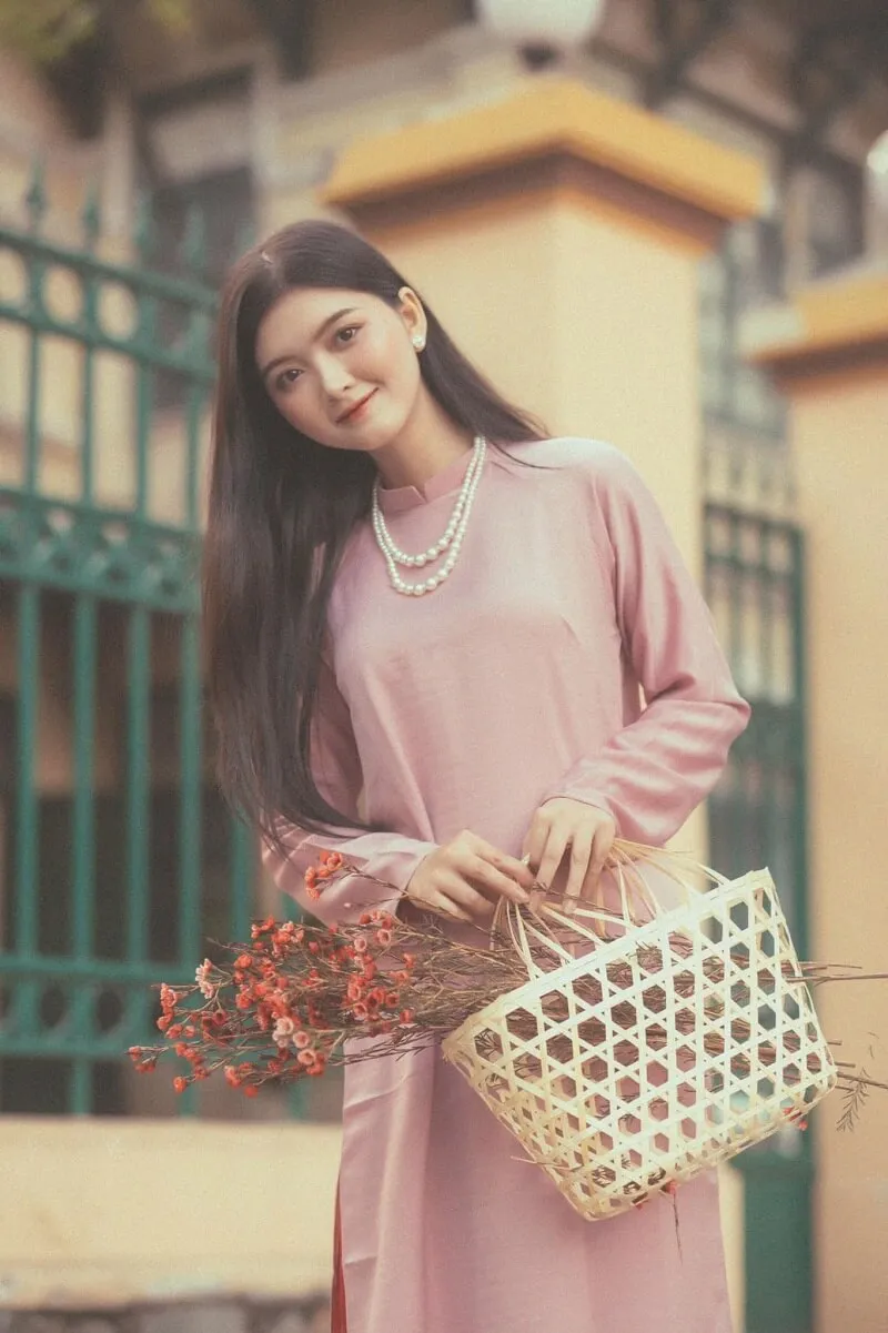 Chụp ảnh tết có một người phụ nữ mặc chiếc váy màu hồng cầm cái giỏ hoa