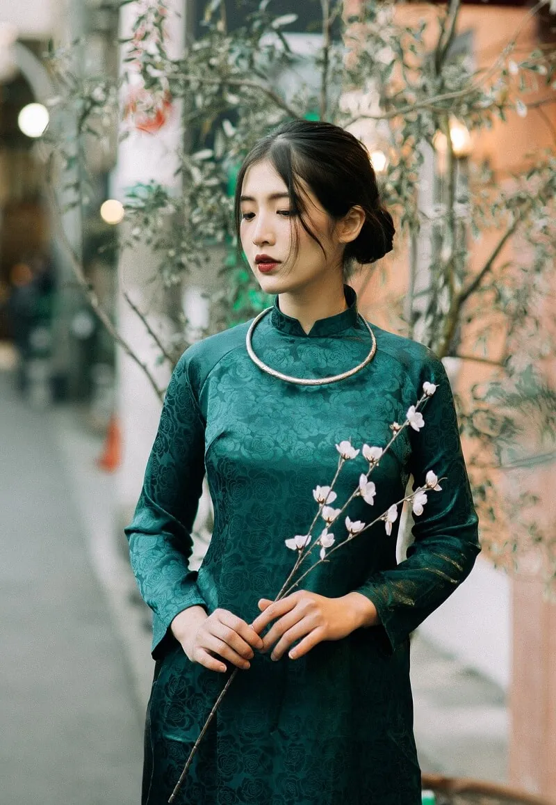 Chụp ảnh tết có một người phụ nữ mặc chiếc váy màu xanh lá cây và cầm bông hoa