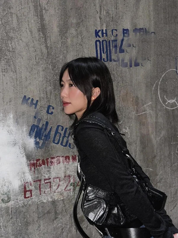 Diệu nhi bikini bức tường bê tông với graffiti trên đó và một người phụ nữ mặc áo khoác da màu đen