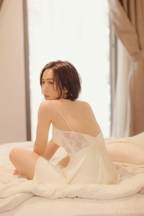 Diệu nhi bikini có một người phụ nữ mặc váy trắng ngồi trên giường