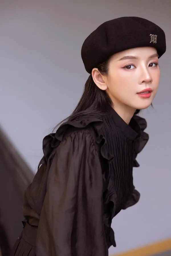 Dj mie người phụ nữ đang đội một chiếc mũ đen và váy