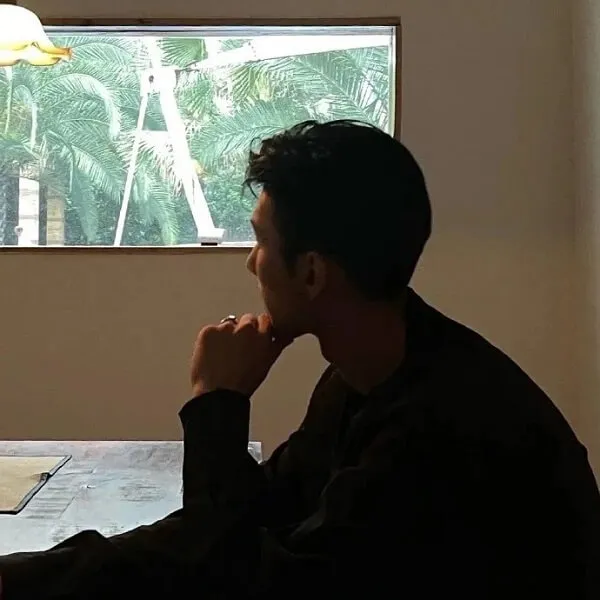 Có một người đàn ông đang ngồi bàn với máy tính xách tay