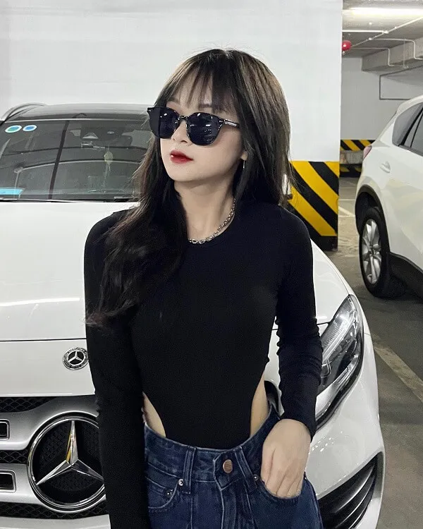 Gấm kami người phụ nữ trong áo đen và quần jean đứng trước một chiếc tô màu trắng