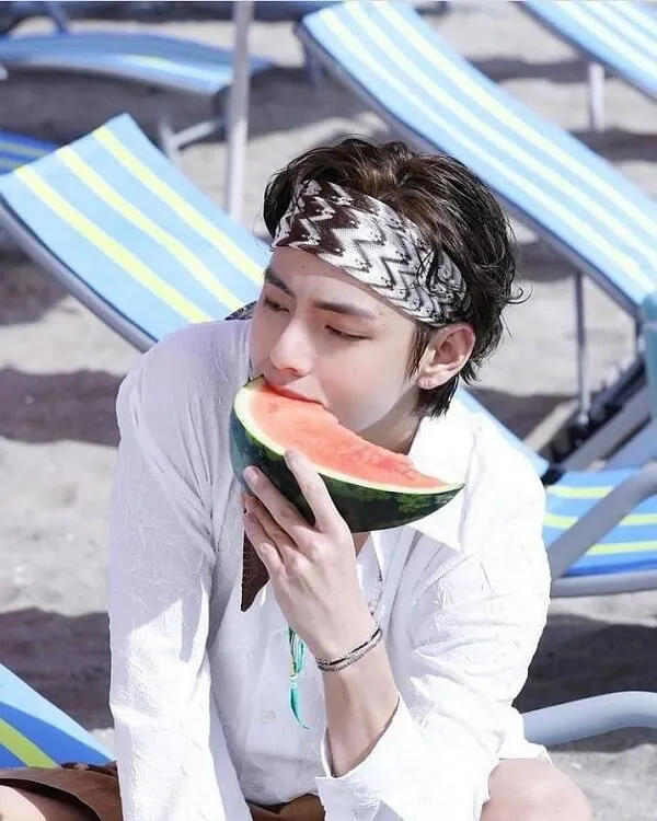 Ảnh bts đây là một người đàn ông ăn lát dưa hấu trên bãi biển