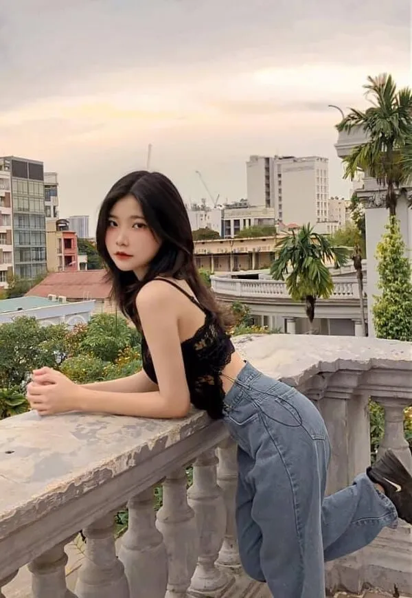 Hình ảnh gái xinh 2k5 có một người phụ nữ đang dựa vào lan can nhìn máy