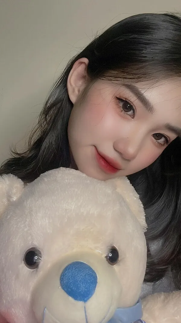 Hình ảnh gái xinh việt nam có một người phụ nữ cầm con gấu bông trắng với mũi màu xanh