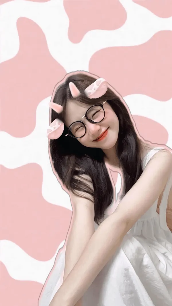 Ảnh gái xinh cute người phụ nữ trẻ đeo kính và một chiếc váy trắng ngồi trên nền in bò màu hồng