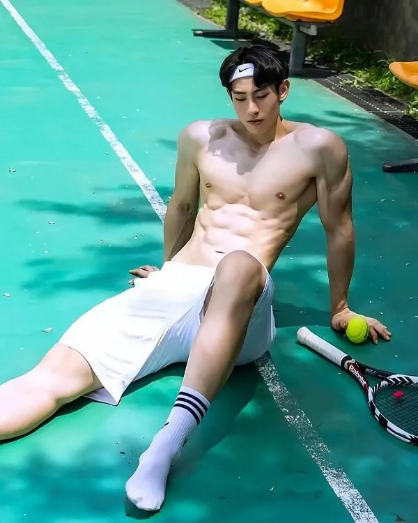 Ảnh hot boy múi có một người đàn ông không mặc áo ngồi trên sân tennis với cây vợt